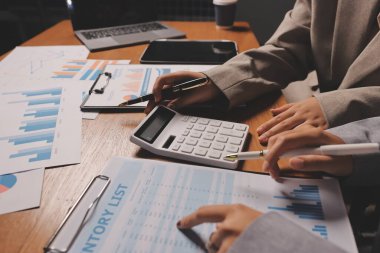 Group of confident business people point to graphs and charts to analyze market data, balance sheet, account, net profit to plan new sales strategies to increase production capacity.