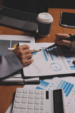 Group of confident business people point to graphs and charts to analyze market data, balance sheet, account, net profit to plan new sales strategies to increase production capacity.