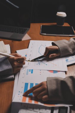 Group of confident business people point to graphs and charts to analyze market data, balance sheet, account, net profit to plan new sales strategies to increase production capacity.