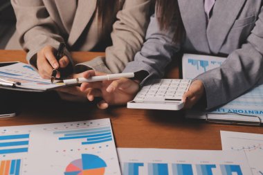 Group of confident business people point to graphs and charts to analyze market data, balance sheet, account, net profit to plan new sales strategies to increase production capacity.