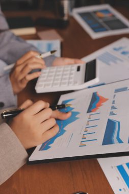 Group of confident business people point to graphs and charts to analyze market data, balance sheet, account, net profit to plan new sales strategies to increase production capacity.