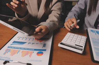 Group of confident business people point to graphs and charts to analyze market data, balance sheet, account, net profit to plan new sales strategies to increase production capacity.