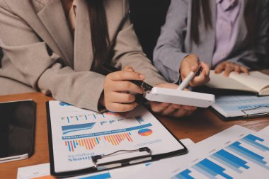 Group of confident business people point to graphs and charts to analyze market data, balance sheet, account, net profit to plan new sales strategies to increase production capacity.