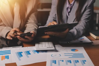 Group of confident business people point to graphs and charts to analyze market data, balance sheet, account, net profit to plan new sales strategies to increase production capacity.