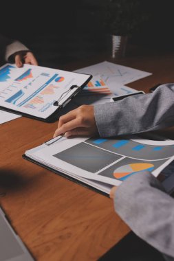 Group of confident business people point to graphs and charts to analyze market data, balance sheet, account, net profit to plan new sales strategies to increase production capacity.