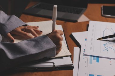 Group of confident business people point to graphs and charts to analyze market data, balance sheet, account, net profit to plan new sales strategies to increase production capacity.