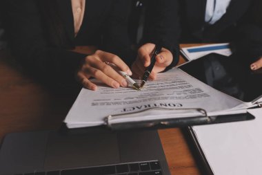 Ofisteki çekici genç avukat iş kadını ve avukatlar ofisdeki ahşap masada pirinç pullu kağıtları tartışıyorlar. Hukuk, hukuk hizmetleri, danışmanlık, Adalet ve emlak kavramı.