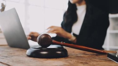 Avukat laptopta çalışıyor, tokmağı da ofisteki ahşap bir masada..