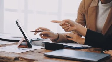 Ofisteki ekrandaki dijital tablete işaret eden iş kadını elini kapat. Arka planda dizüstü bilgisayar kullanan genç bir kadın.