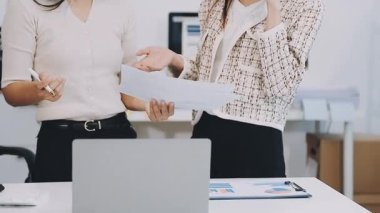 Ofiste iki iş kadını elinde belgeler tutuyor.