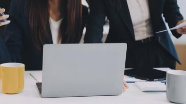 Yakın plan - ofiste çalışan genç iş kadınlarının dizüstü bilgisayarı tutup iş yerinde konuşmaları