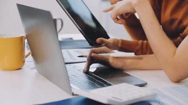 Masasında tablet ve bilgisayarla ofiste çalışan bir kadın.