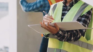 Üniformalı ve miğferli işçiler ellerinde kağıtlar, yakın plan.