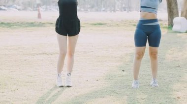 İki genç kız parkta egzersiz yapıyor.