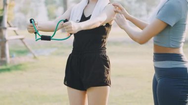 Kadın parkta elastik bantla spor yapıyor..