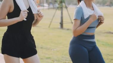 Genç Asyalı kadınlar yeşil çimlerde koşuyor.