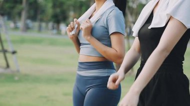 Asyalı kadın parkta dambıllarla egzersiz yapıyor.