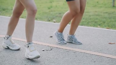 Parktaki pistte spor elbiseli genç bir kadın koşuyor.