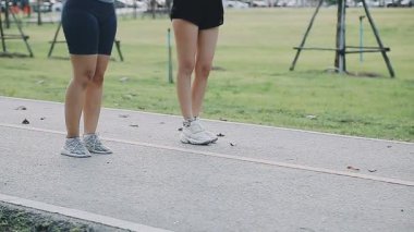 Spor kıyafetli bir kadın koşu bandında bacaklarını açıyor.