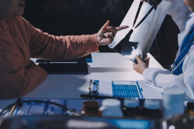 Doktor, emekliye ayrılmış yaşlı kadına akciğer röntgeni çeken hastanın sağlık ve hayat sigortası planlarını kullanarak hastane bakım evindeki hastalara tedavi yöntemlerini anlattı.