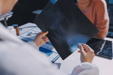 Doktor, emekliye ayrılmış yaşlı kadına akciğer röntgeni çeken hastanın sağlık ve hayat sigortası planlarını kullanarak hastane bakım evindeki hastalara tedavi yöntemlerini anlattı.