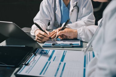 Erkek ve kadın doktorlar bir hastane odasında toplantı yapıyorlar..