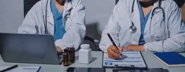 Erkek ve kadın doktorlar bir hastane odasında toplantı yapıyorlar..