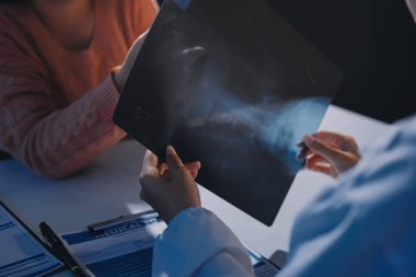 Doktor, emekliye ayrılmış yaşlı kadına akciğer röntgeni çeken hastanın sağlık ve hayat sigortası planlarını kullanarak hastane bakım evindeki hastalara tedavi yöntemlerini anlattı.