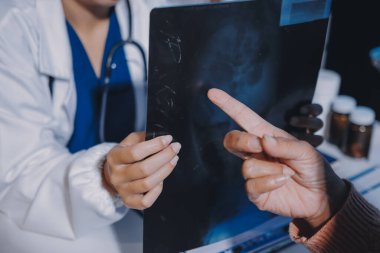 Doktor, emekliye ayrılmış yaşlı kadına akciğer röntgeni çeken hastanın sağlık ve hayat sigortası planlarını kullanarak hastane bakım evindeki hastalara tedavi yöntemlerini anlattı.