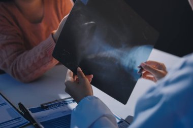 Doktor, emekliye ayrılmış yaşlı kadına akciğer röntgeni çeken hastanın sağlık ve hayat sigortası planlarını kullanarak hastane bakım evindeki hastalara tedavi yöntemlerini anlattı.