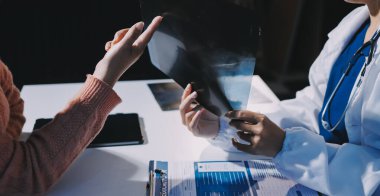 Doktor, emekliye ayrılmış yaşlı kadına akciğer röntgeni çeken hastanın sağlık ve hayat sigortası planlarını kullanarak hastane bakım evindeki hastalara tedavi yöntemlerini anlattı.