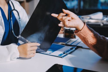 Doktor, emekliye ayrılmış yaşlı kadına akciğer röntgeni çeken hastanın sağlık ve hayat sigortası planlarını kullanarak hastane bakım evindeki hastalara tedavi yöntemlerini anlattı.