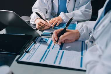 Erkek ve kadın doktorlar bir hastane odasında toplantı yapıyorlar..