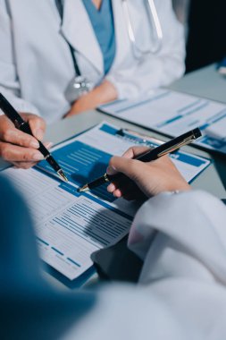 Erkek ve kadın doktorlar bir hastane odasında toplantı yapıyorlar..