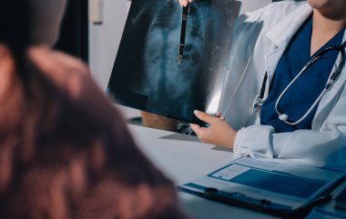 Doktor, emekliye ayrılmış yaşlı kadına akciğer röntgeni çeken hastanın sağlık ve hayat sigortası planlarını kullanarak hastane bakım evindeki hastalara tedavi yöntemlerini anlattı.