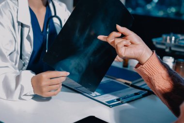 Doktor, emekliye ayrılmış yaşlı kadına akciğer röntgeni çeken hastanın sağlık ve hayat sigortası planlarını kullanarak hastane bakım evindeki hastalara tedavi yöntemlerini anlattı.