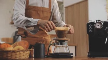 Kahve dükkanında kahve yapan genç barista.