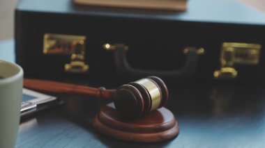 Tokmak ve hukuk kitabı arka planda masanın üzerinde.