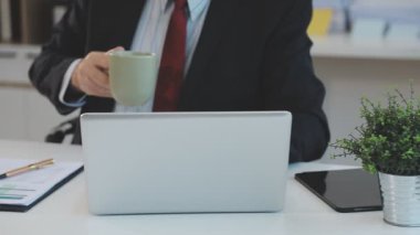 İşadamı ofisinde dizüstü bilgisayar ve akıllı telefon kullanıyor..