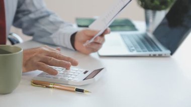 Ofiste hesap makinesi ve dizüstü bilgisayar kullanan bir iş adamı.