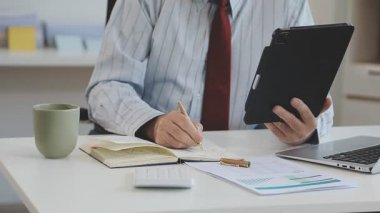 Ofiste çalışan belge ve iş adamlarıyla birlikte tablet bilgisayar kullanan işadamı, mali rapor ve iş konsepti