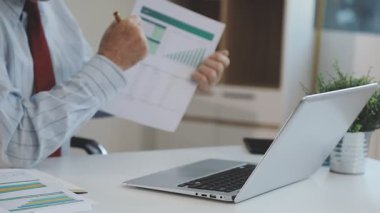 Ofiste mali belgelerle çalışan genç adam, yakın plan.