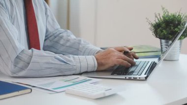 Genç işadamı ofiste dizüstü bilgisayarda çalışıyor, yakın plan.