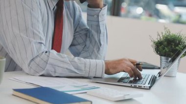 Ofiste çalışan işadamı, dizüstü bilgisayar ve iş belgeleri