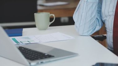 İş adamı dizüstü bilgisayar ve bardak kullanıyor.