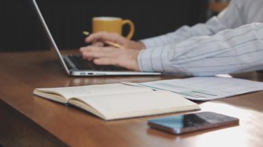 Dizüstü bilgisayarla çalışan ve not defterinde yazan iş adamı