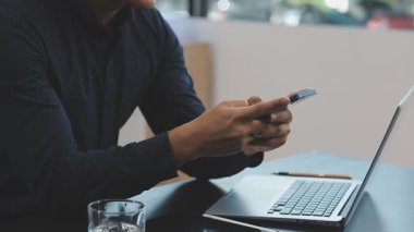 Ofisteki masada akıllı telefonu ve bilgisayarı olan adam.