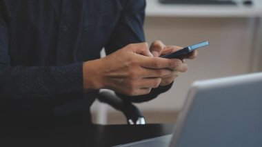 Genç yakışıklı adam evde cep telefonu kullanıyor.