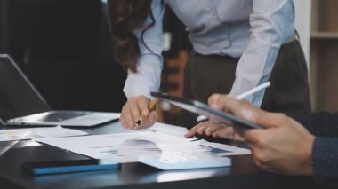 İşadamları ofiste dizüstü bilgisayarla ve belgelerle çalışıyorlar.