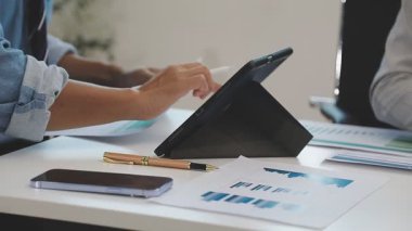 İşadamı elinde dijital tablet kullanarak kalem tutuyor ve iş yerinde verileri tartışıyor